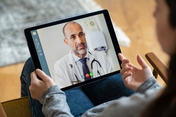 A person using a tablet for a virtual visit with a doctor.