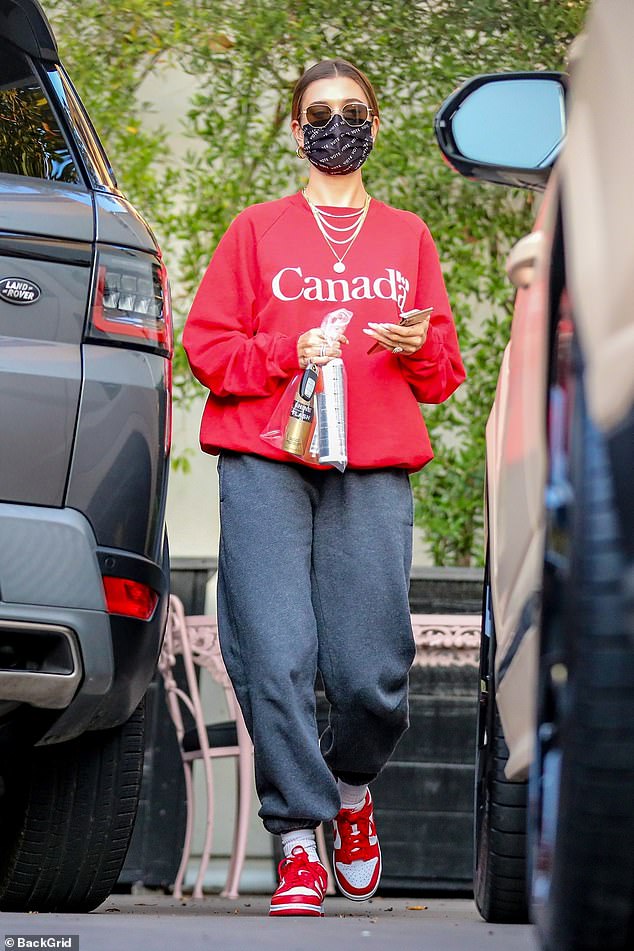 Proud: Hailey Bieber represented the hometown of her husband Justin Bieber by donning a red crew-neck jacket from Canada during a salon trip in Los Angeles on Wednesday.