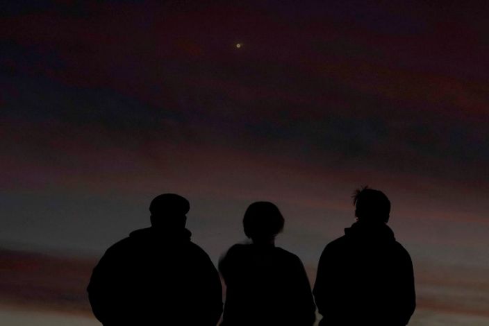 People are shaded in front of the sky at dusk as they watch the alignment of Saturn and Jupiter, Monday, December 21, 2020, in Edgerton, Cannes.
