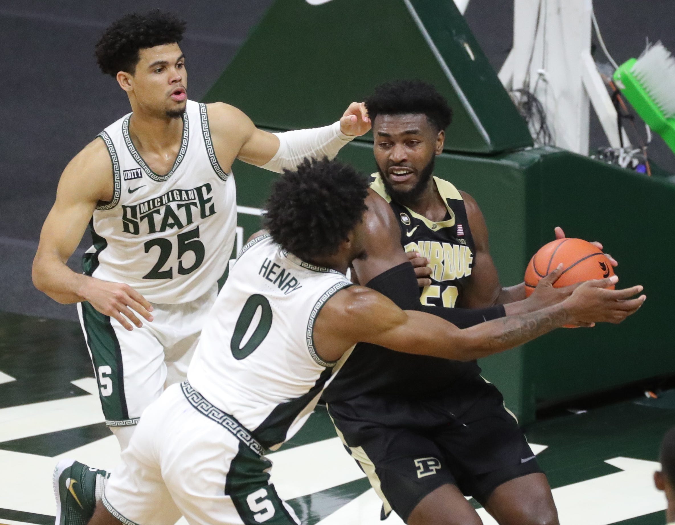 Michigan State Spartans striker Malik Hall (25) and Aaron Henry defend Purdue Boilermakers striker Trevion Williams during the second half at Priceline Center in East Lansing, Friday, Jan.8, 2021.