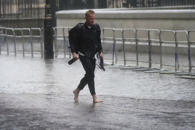 A man walks barefoot on a flooded street in central London on July 25.