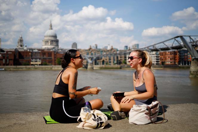 Two friends sit by the River Thames in London as the temperature rises to 31°C on June 26, 2020.