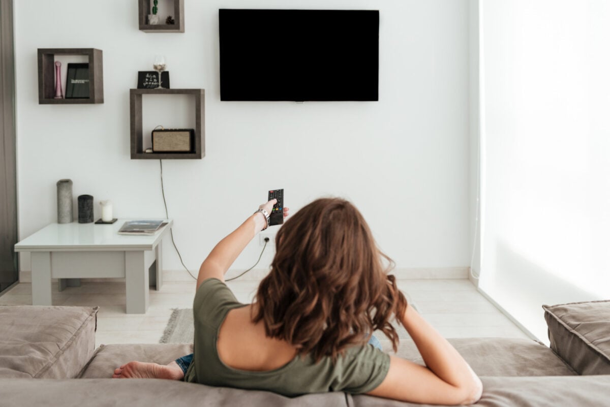 Watching wallpaper of a model woman sitting on a sofa and watching TV at home